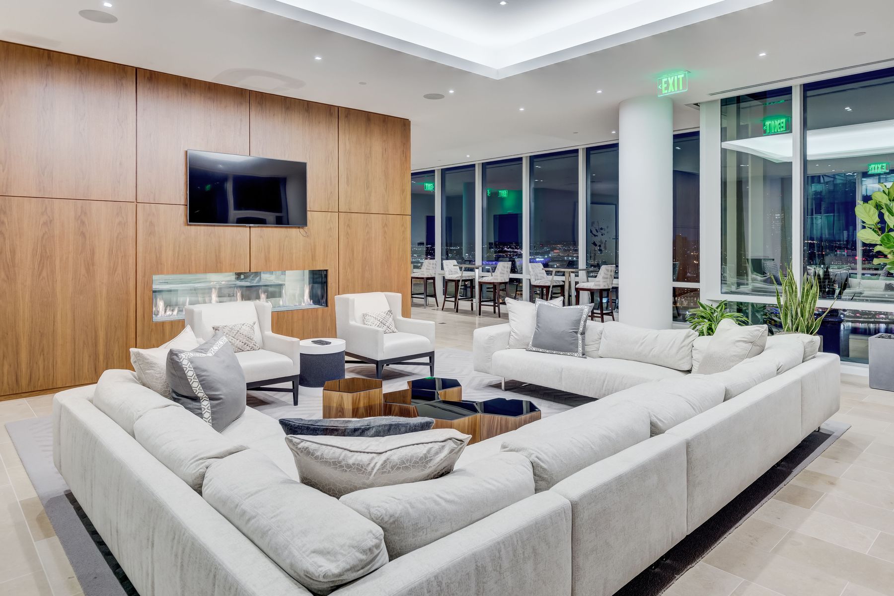 Shared lounge with pale sofas surrounding a coffee table and a wood-paneled television wall