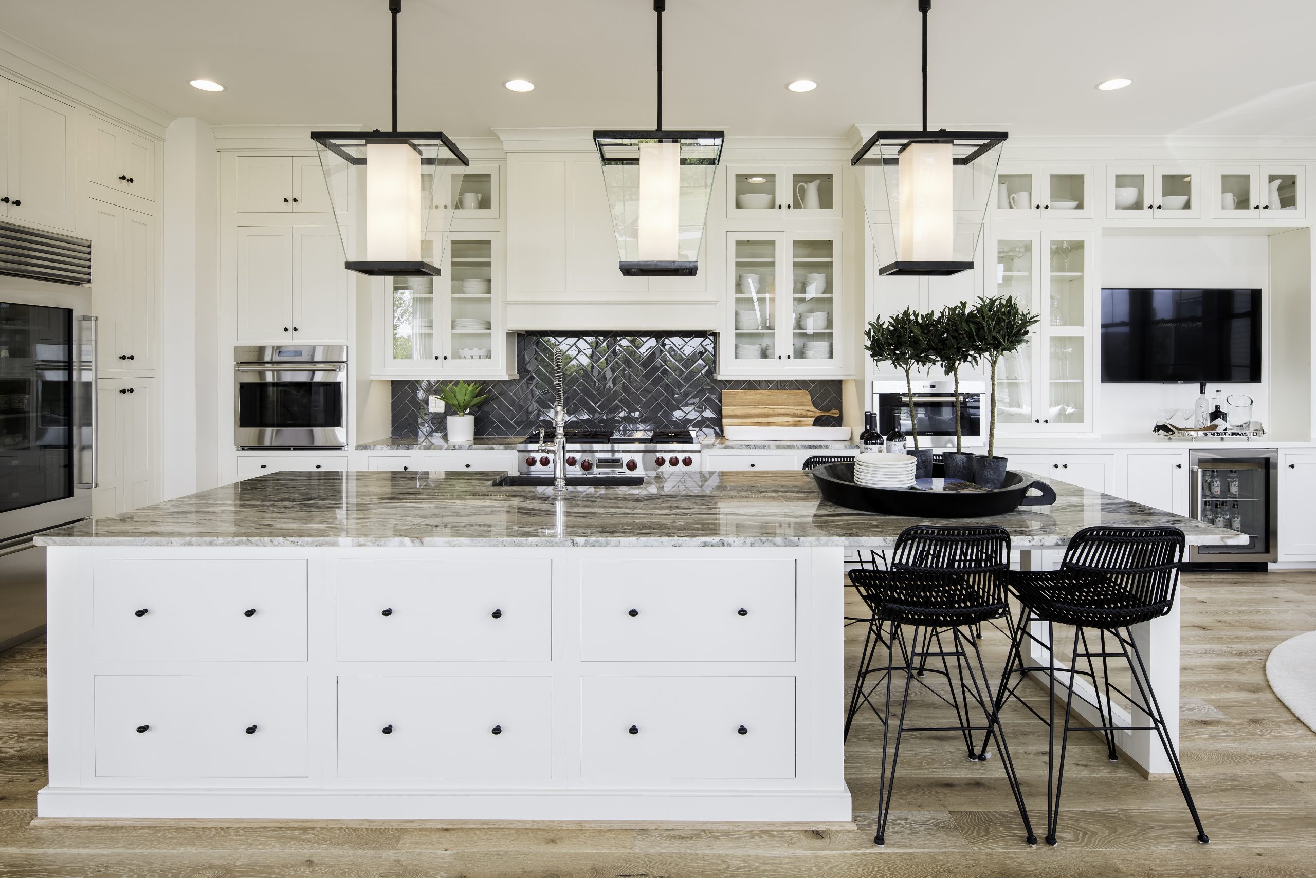 White kitchen cabinetry with dark backsplash and lantern pendants