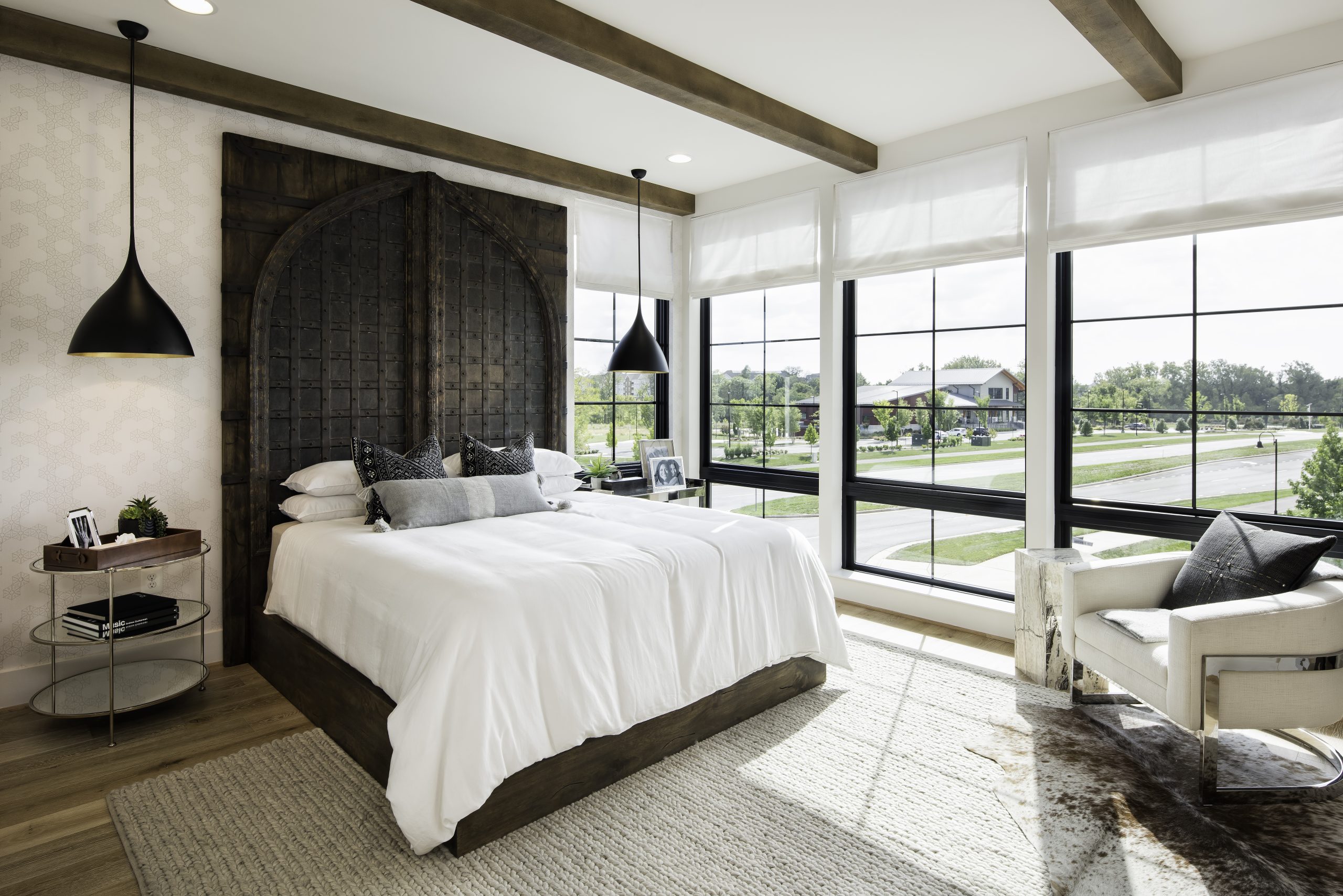 Bedroom with a tall dark headboard and wood ceiling beams