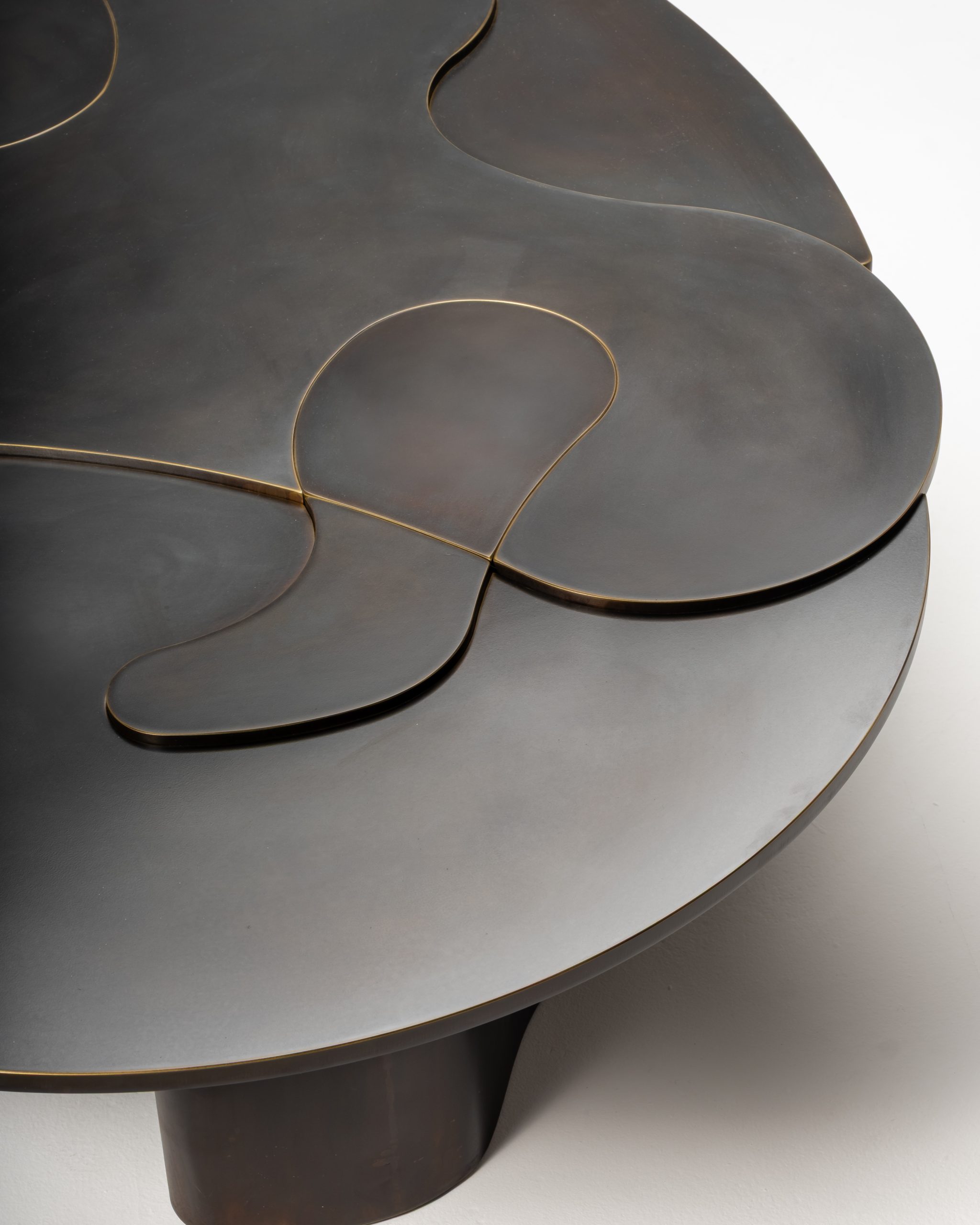 The layered tabletop and the brass revealed along its curved edges.