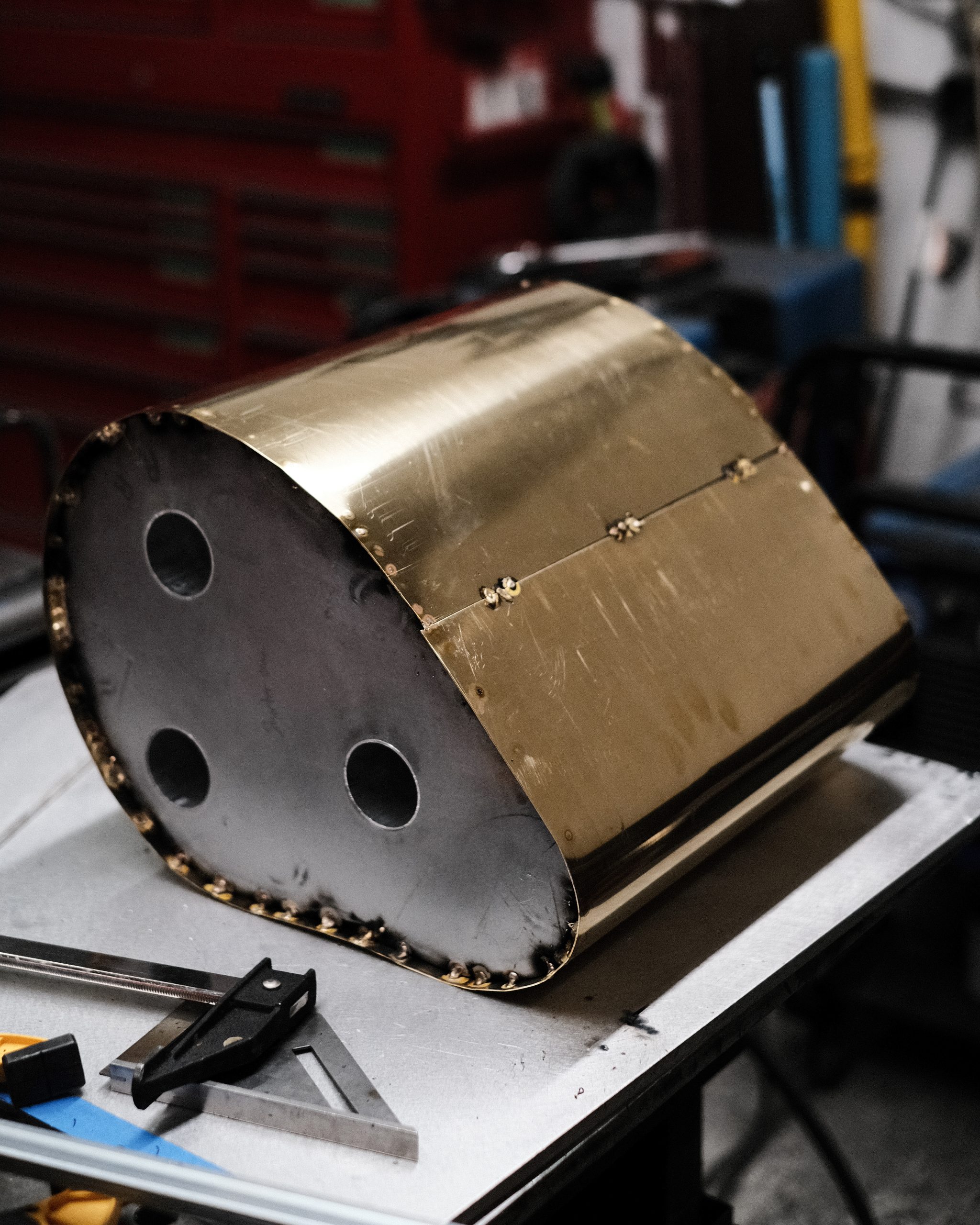 A curved brass support with its seam and weld points visible.